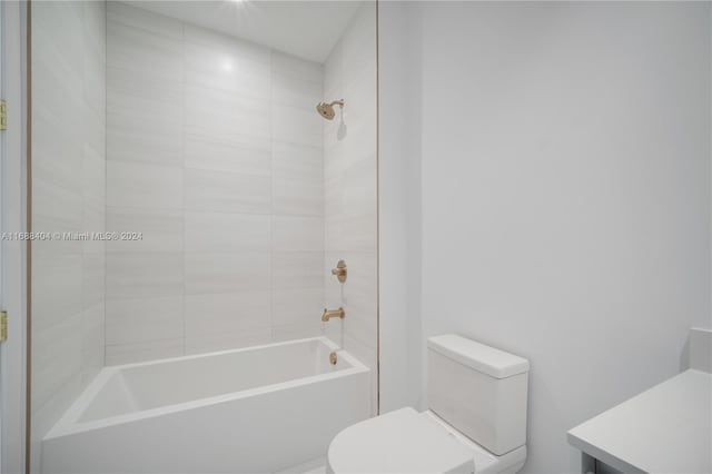 full bathroom featuring toilet, tiled shower / bath combo, and vanity