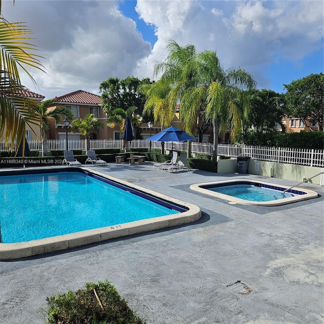 view of swimming pool with a hot tub and a patio area