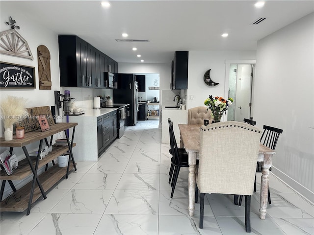 kitchen with tasteful backsplash, sink, a kitchen breakfast bar, and stainless steel appliances