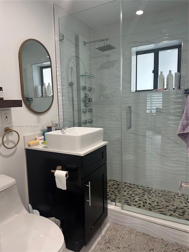 bathroom with a shower with shower door, vanity, and toilet