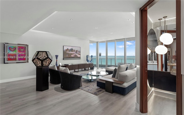 living room featuring hardwood / wood-style floors, a wall of windows, and a water view