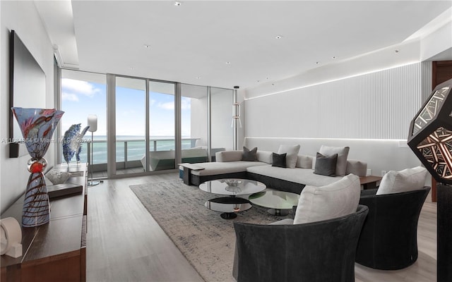 living room with a wall of windows, light hardwood / wood-style flooring, and a water view