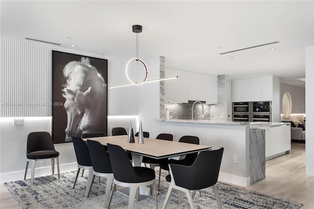 dining space featuring light wood-type flooring and sink