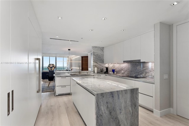 kitchen with white cabinetry, light wood-type flooring, and a kitchen island