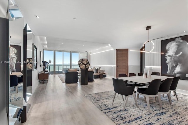 dining area featuring light wood-type flooring, expansive windows, and a water view