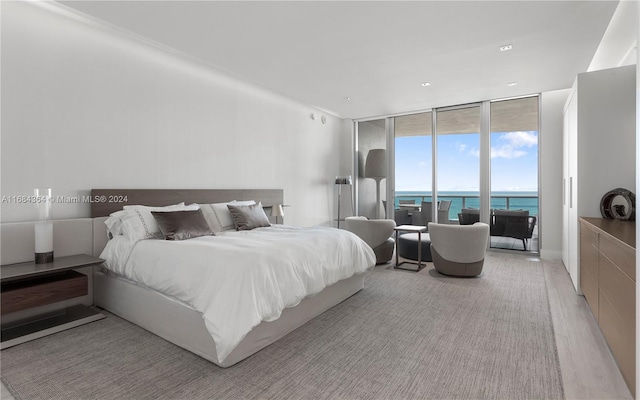 bedroom with a water view, floor to ceiling windows, access to exterior, and light hardwood / wood-style flooring