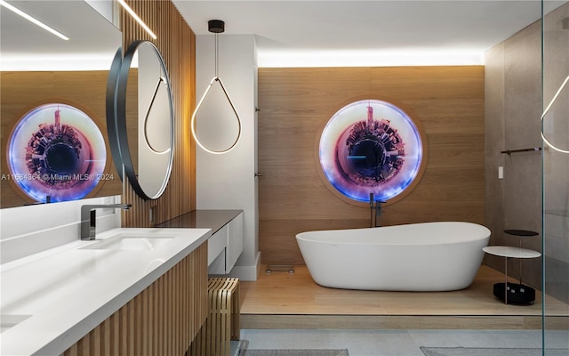 bathroom featuring wood walls, vanity, and a tub to relax in