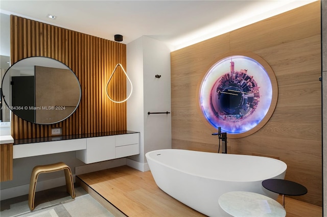 bathroom with vanity, hardwood / wood-style flooring, a washtub, and wooden walls