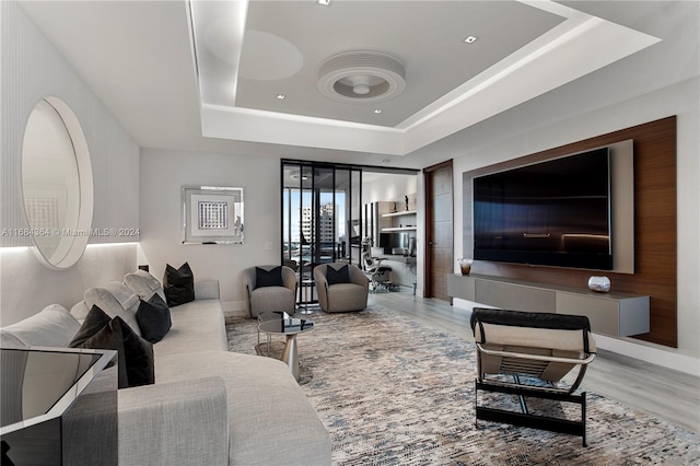 living room with hardwood / wood-style floors and a tray ceiling