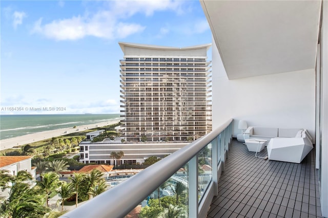 balcony featuring a view of the beach, outdoor lounge area, and a water view