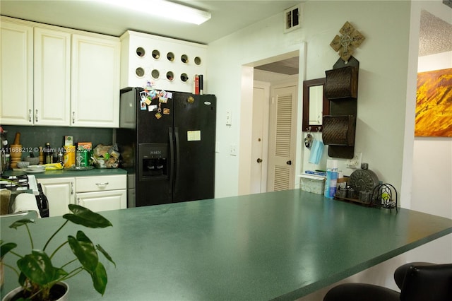 kitchen with white cabinetry, kitchen peninsula, and black refrigerator with ice dispenser