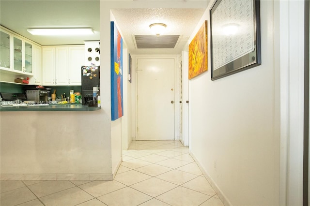 hallway with a textured ceiling and light tile patterned floors