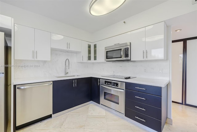 kitchen with tasteful backsplash, sink, white cabinets, and appliances with stainless steel finishes