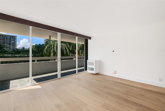 empty room featuring floor to ceiling windows and light wood-type flooring