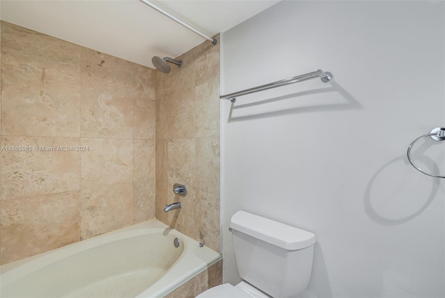 bathroom featuring tiled shower / bath combo and toilet