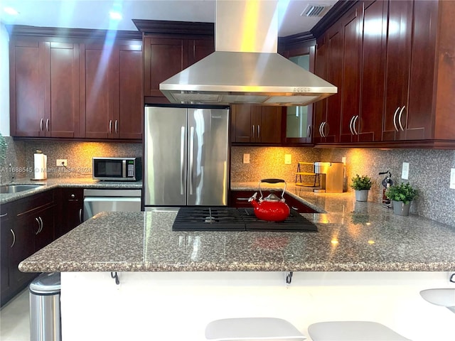 kitchen featuring stainless steel appliances, wall chimney exhaust hood, and tasteful backsplash