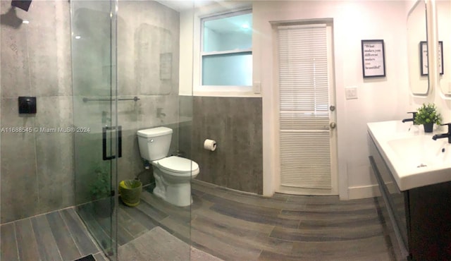 bathroom with toilet, an enclosed shower, vanity, and wood-type flooring