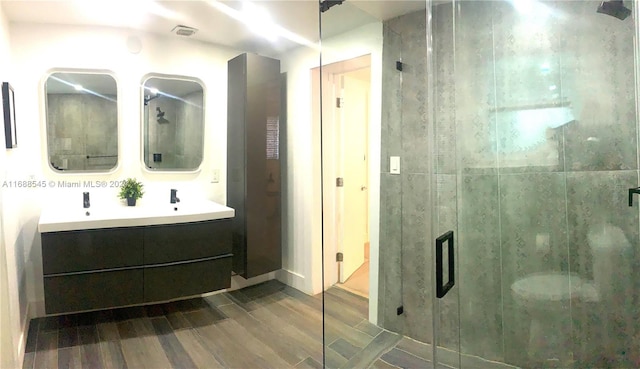 bathroom with hardwood / wood-style floors, vanity, and a shower with door