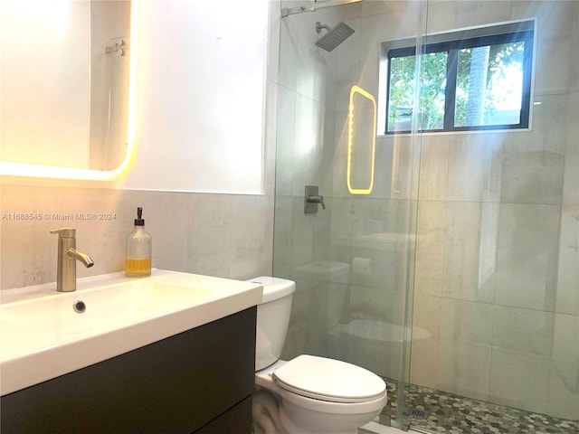 bathroom with toilet, an enclosed shower, vanity, and tile walls