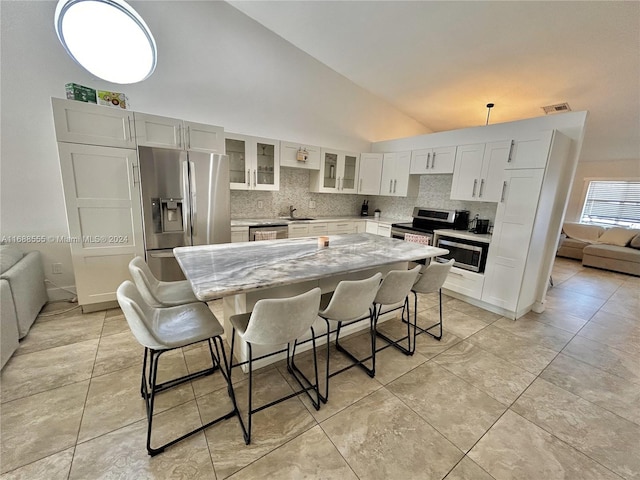 kitchen featuring sink, appliances with stainless steel finishes, backsplash, lofted ceiling, and a center island