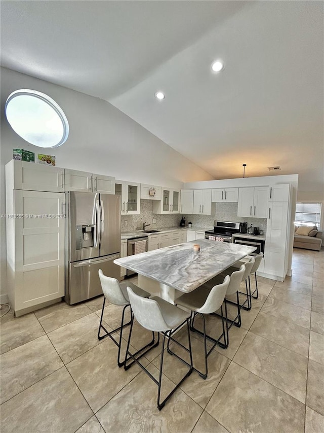 kitchen featuring backsplash, appliances with stainless steel finishes, sink, lofted ceiling, and a center island