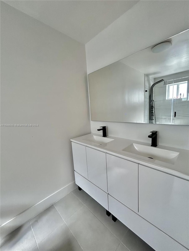 bathroom with tile patterned flooring, vanity, and a tile shower