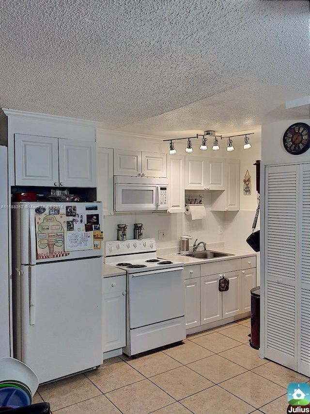 kitchen with sink, light tile patterned floors, a textured ceiling, white appliances, and white cabinets