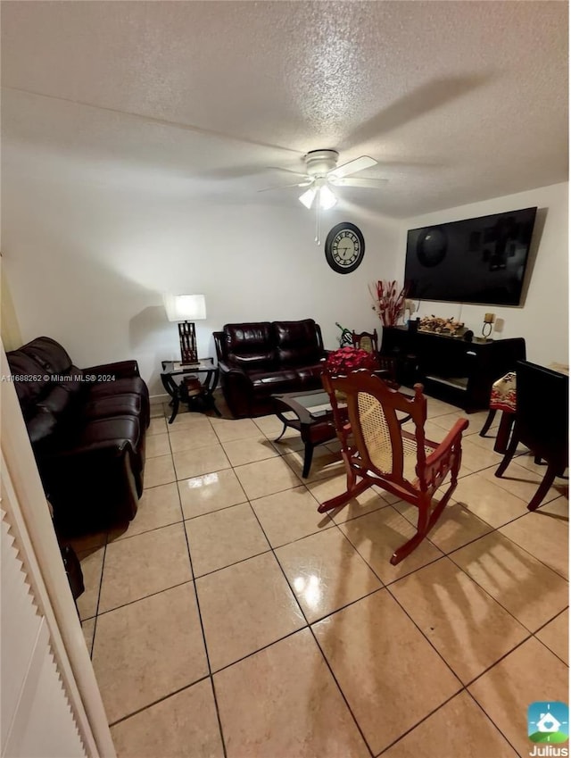 living room with ceiling fan, light tile patterned flooring, and a textured ceiling