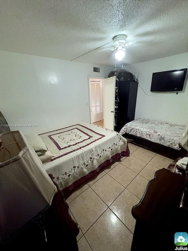 tiled bedroom with ceiling fan and a textured ceiling