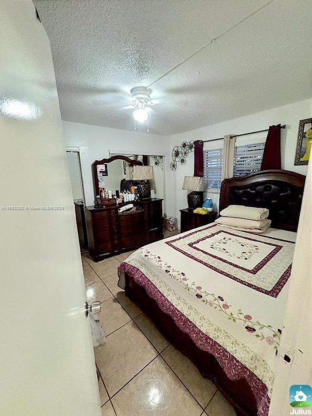 bedroom with tile patterned floors, ceiling fan, and a textured ceiling