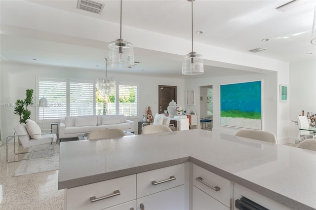 kitchen with a chandelier, white cabinetry, and pendant lighting