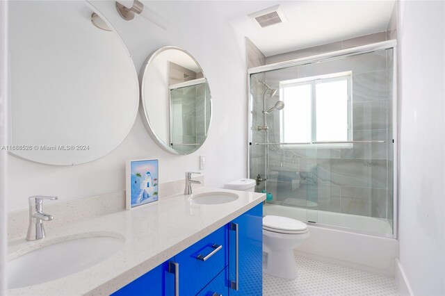 full bathroom featuring enclosed tub / shower combo, tile patterned flooring, vanity, and toilet