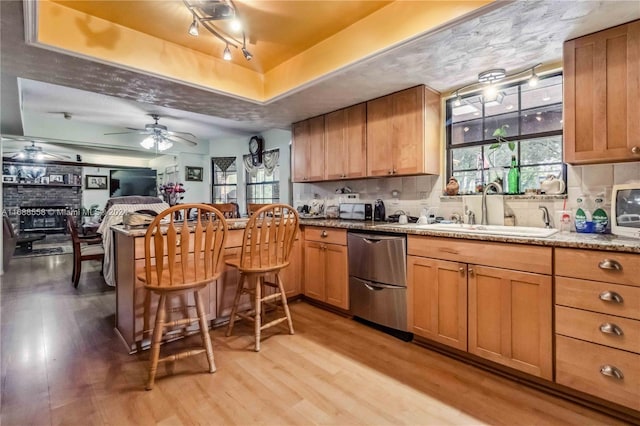 kitchen featuring backsplash, sink, dishwasher, ceiling fan, and light hardwood / wood-style flooring