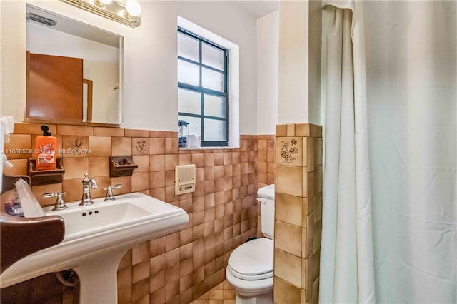 bathroom with toilet and tile walls