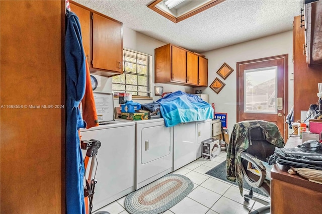 washroom with cabinets, a textured ceiling, light tile patterned flooring, and washer and dryer