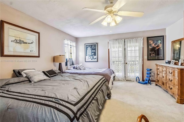 bedroom featuring a textured ceiling, light colored carpet, multiple windows, and ceiling fan