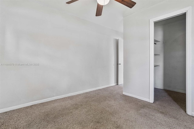 unfurnished bedroom featuring a closet, carpet floors, ceiling fan, and a spacious closet