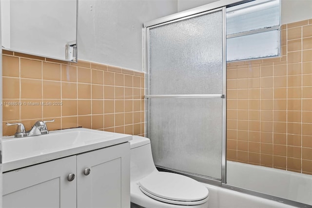 full bathroom with vanity, tile walls, shower / bath combination with glass door, and toilet