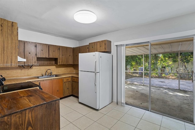 kitchen with electric range oven, sink, decorative backsplash, white fridge, and light tile patterned floors