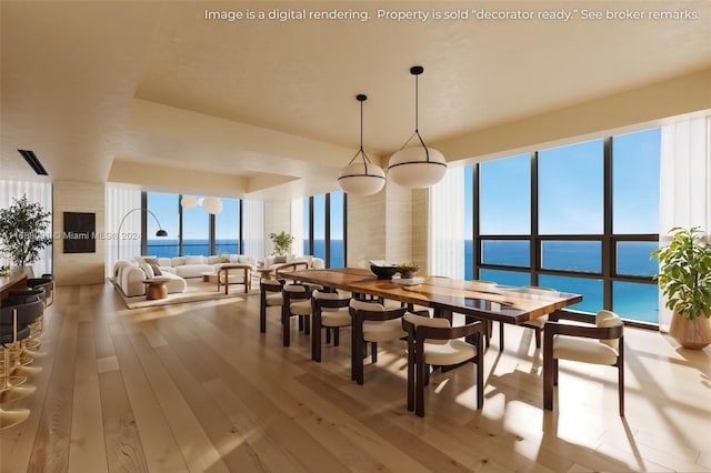 dining room featuring light wood-type flooring, a water view, and a healthy amount of sunlight