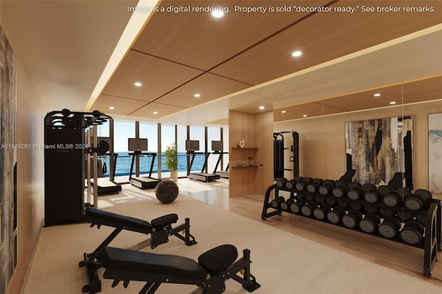 gym featuring expansive windows, a water view, and light colored carpet