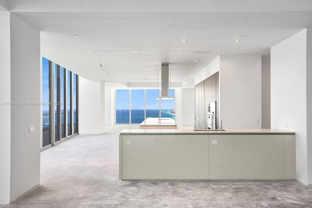 kitchen with expansive windows, island exhaust hood, sink, and a water view