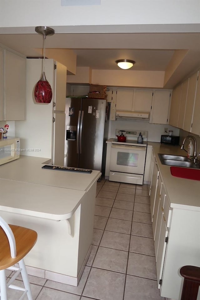 kitchen with kitchen peninsula, sink, light tile patterned floors, a breakfast bar, and white appliances