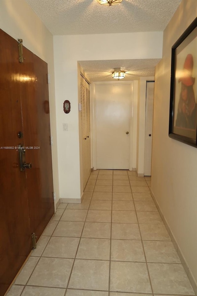 hall featuring a textured ceiling and light tile patterned floors