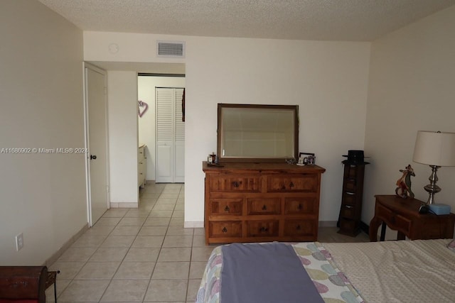 tiled bedroom featuring a textured ceiling and a closet