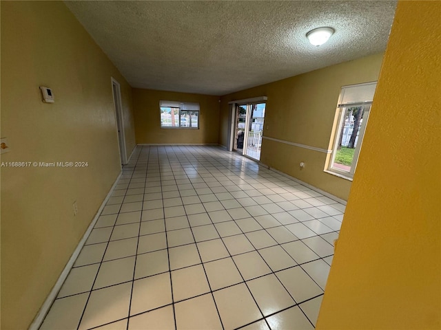 tiled empty room featuring a textured ceiling