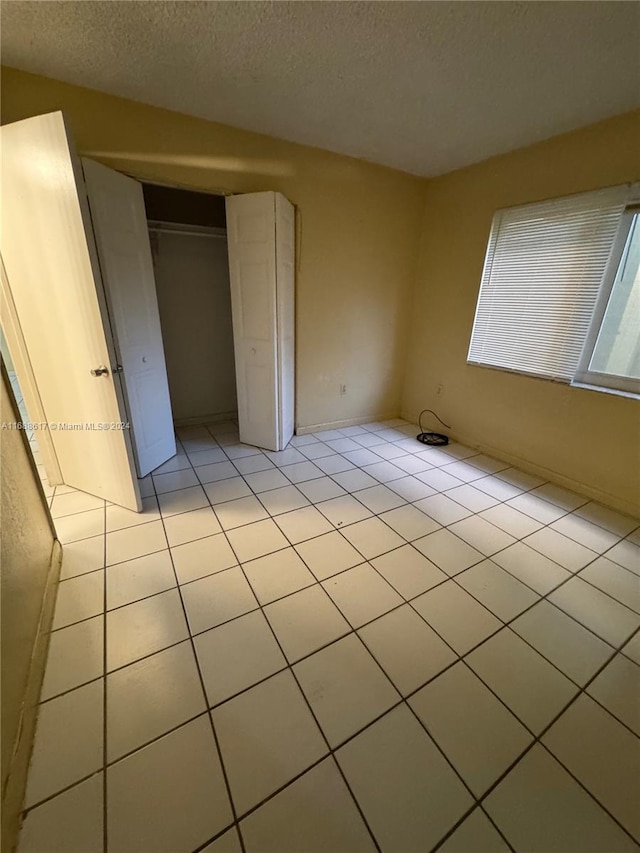 unfurnished bedroom featuring light tile patterned floors, a textured ceiling, and a closet