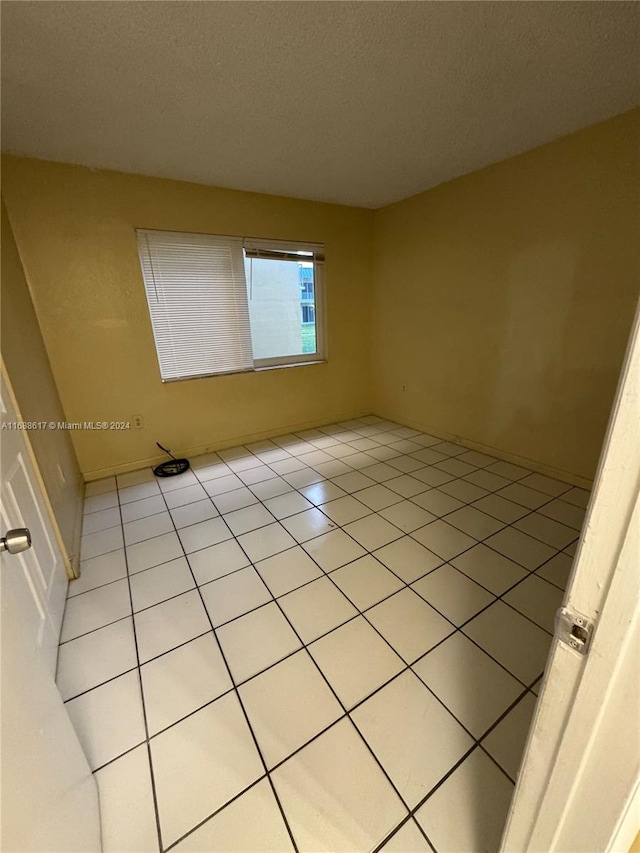 unfurnished room featuring a textured ceiling and light tile patterned flooring