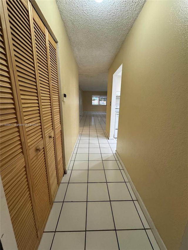 corridor featuring a textured ceiling and light tile patterned floors