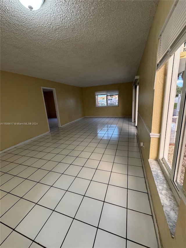 unfurnished room with a textured ceiling, a healthy amount of sunlight, and light tile patterned flooring